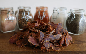 ayoba-yo biltong. grass fed and keto certified beef snack on wood table with natural seasonings.